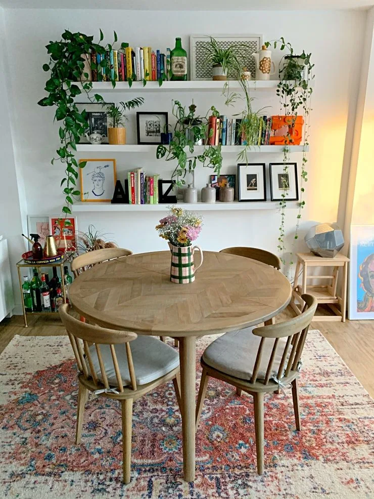 floating shelves in dining room wall and round dining table and chairs with rectangular rug