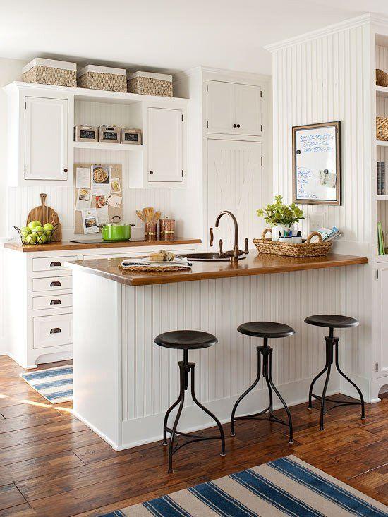 accent boxes or storage boxes above white cabinets and theme or kitchen is white having different kitchen items