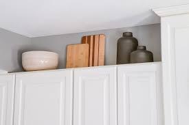 cutting borad-ceramic bowl and jar above white kitchen cabinets