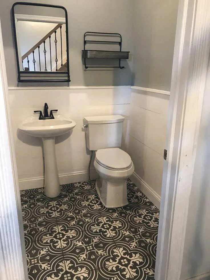 This image may contain; white sink and commode seat with black wall rack and mirror, white tiles on half wall with black and white patterned floor tiles 