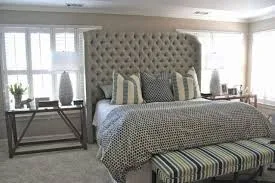 grey headboard for bed with pillows, comforter and beautiful side table having lamp and vase