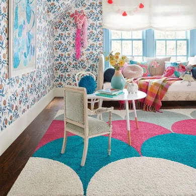 floor rug in playroom with table, chair and sofa. Also have floral wall paper with blue theme